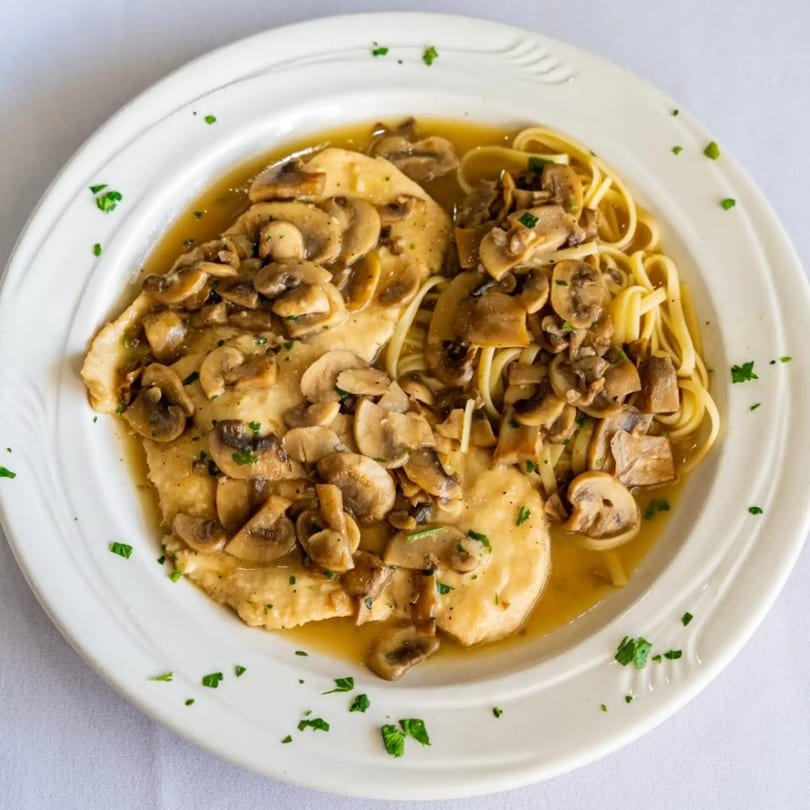 Tuscan Bistro's chicken and mushroom dish with linguine pasta in a savory sauce on a white plate.
